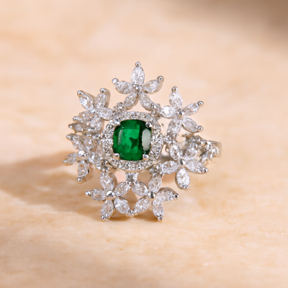 Diamond ring with a central emerald stone on a beige background