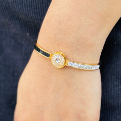 Gold and silver bracelet on a wrist with a blurred background