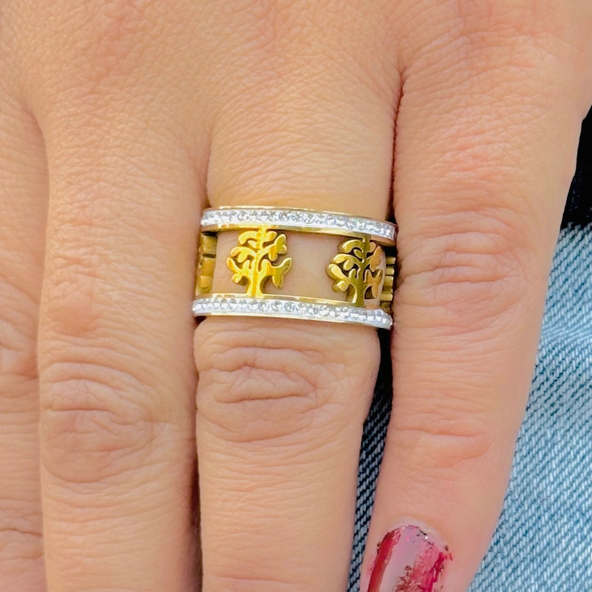 Gold and silver ring with tree design on a finger