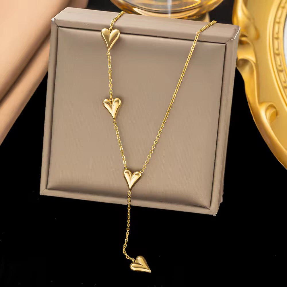 Gold heart-shaped necklace on a beige jewelry box with a black background