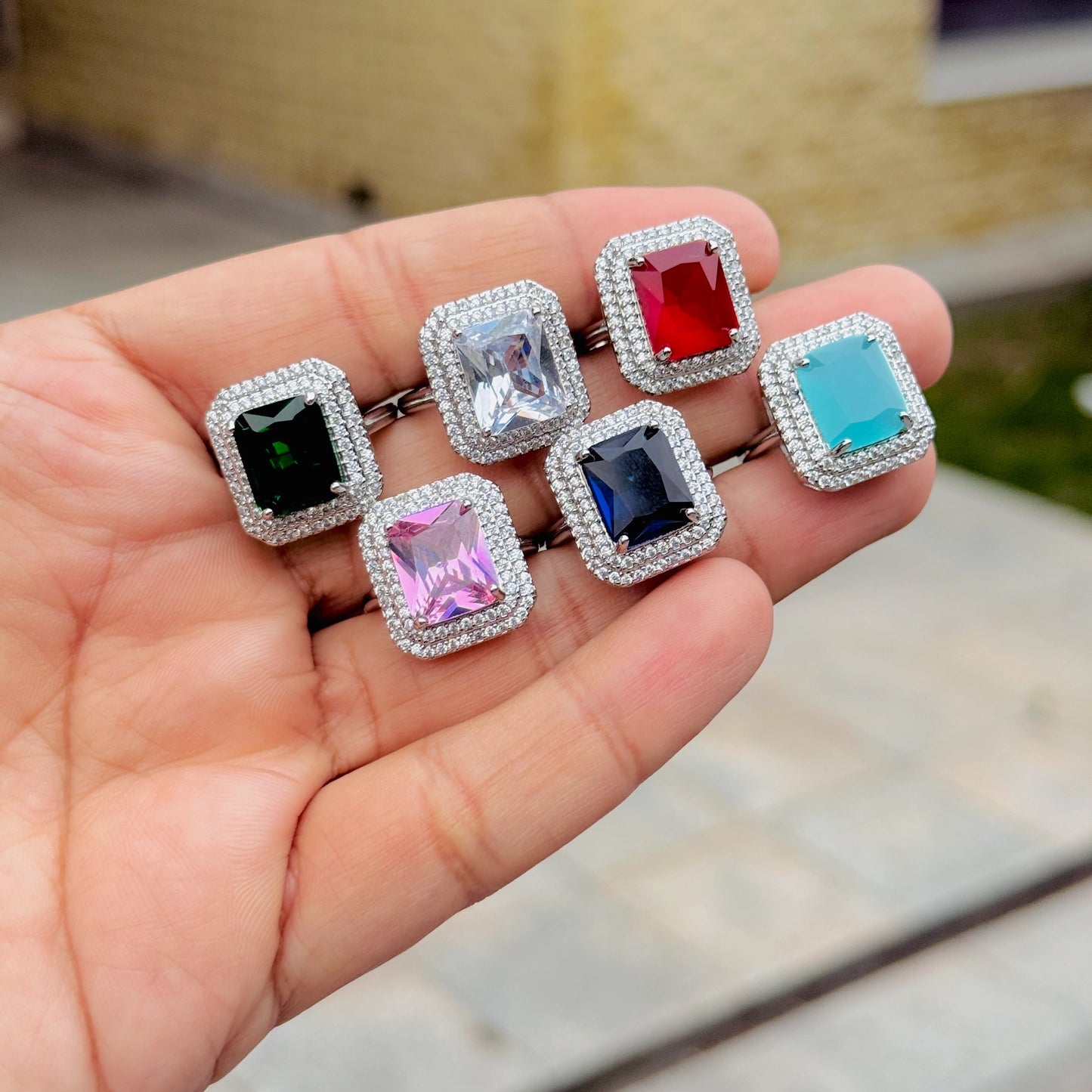Set of colorful gemstone rings held in a hand with a blurred background