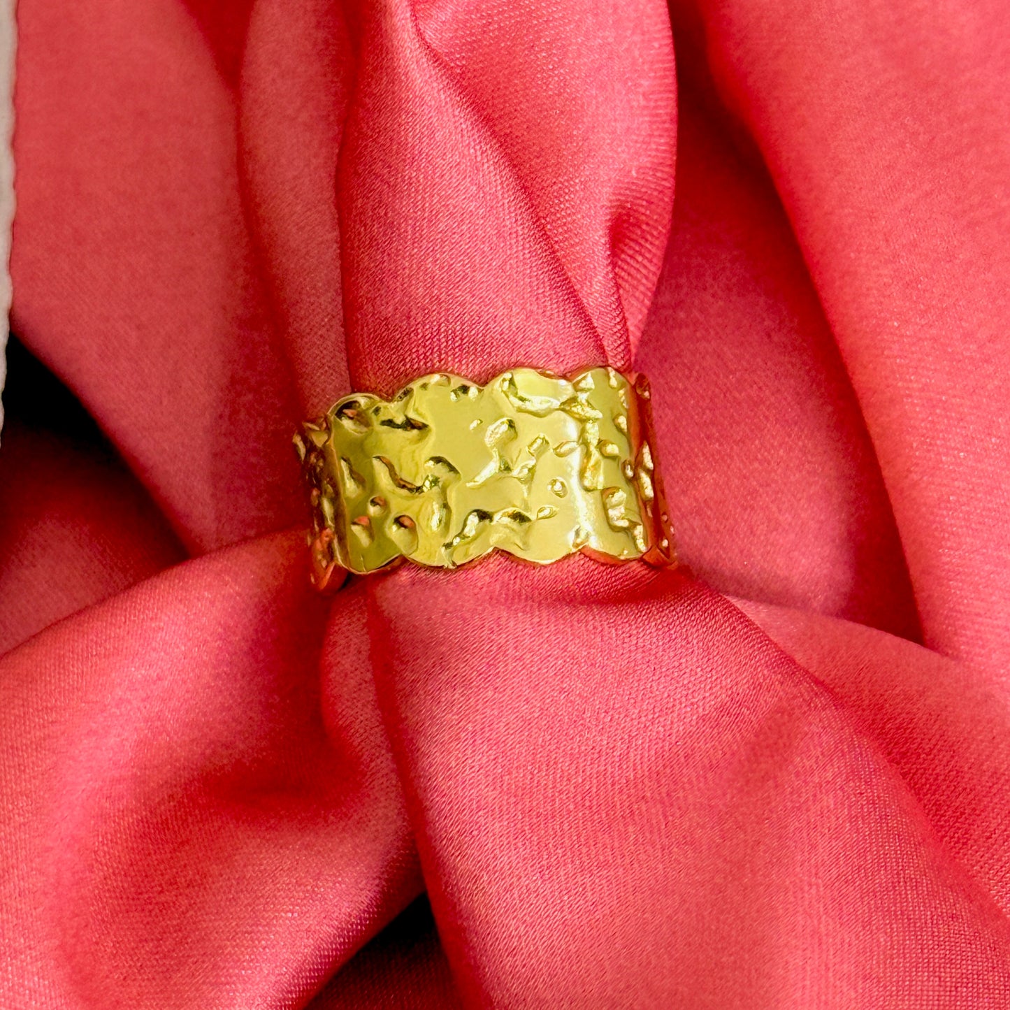 Gold textured ring on a pink fabric background
