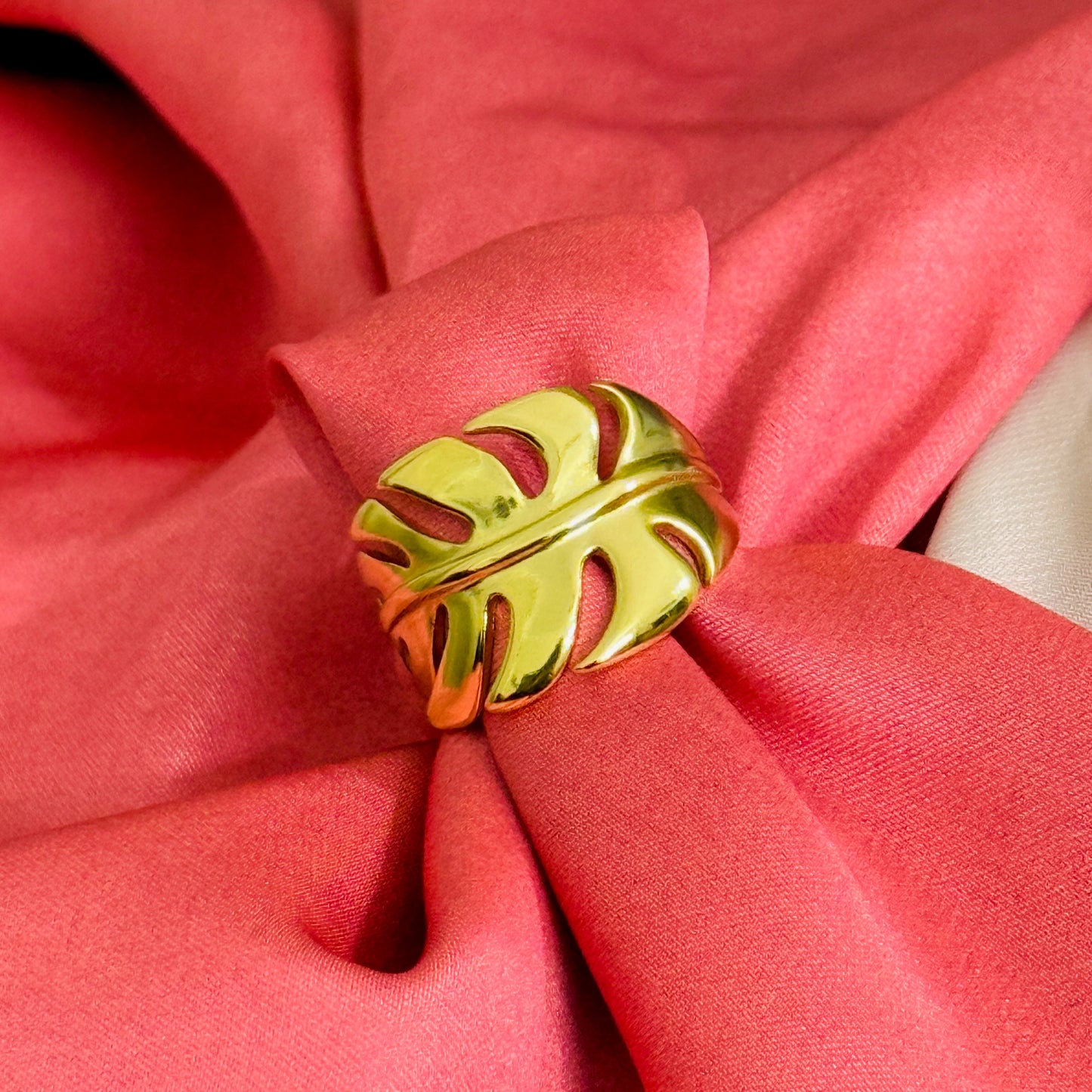 Gold leaf-shaped napkin ring on a pink fabric background