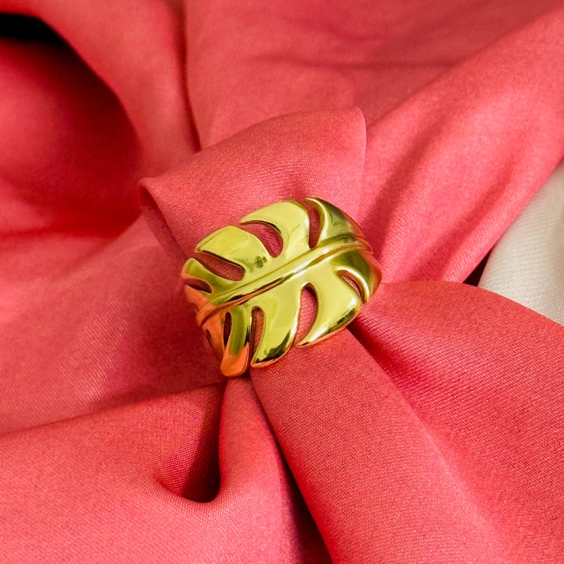 Gold leaf-shaped napkin ring on a pink fabric background