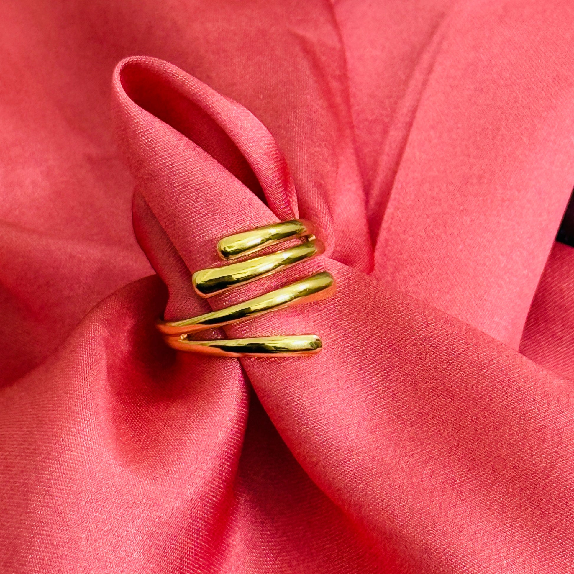 Gold spiral ring on a pink fabric background