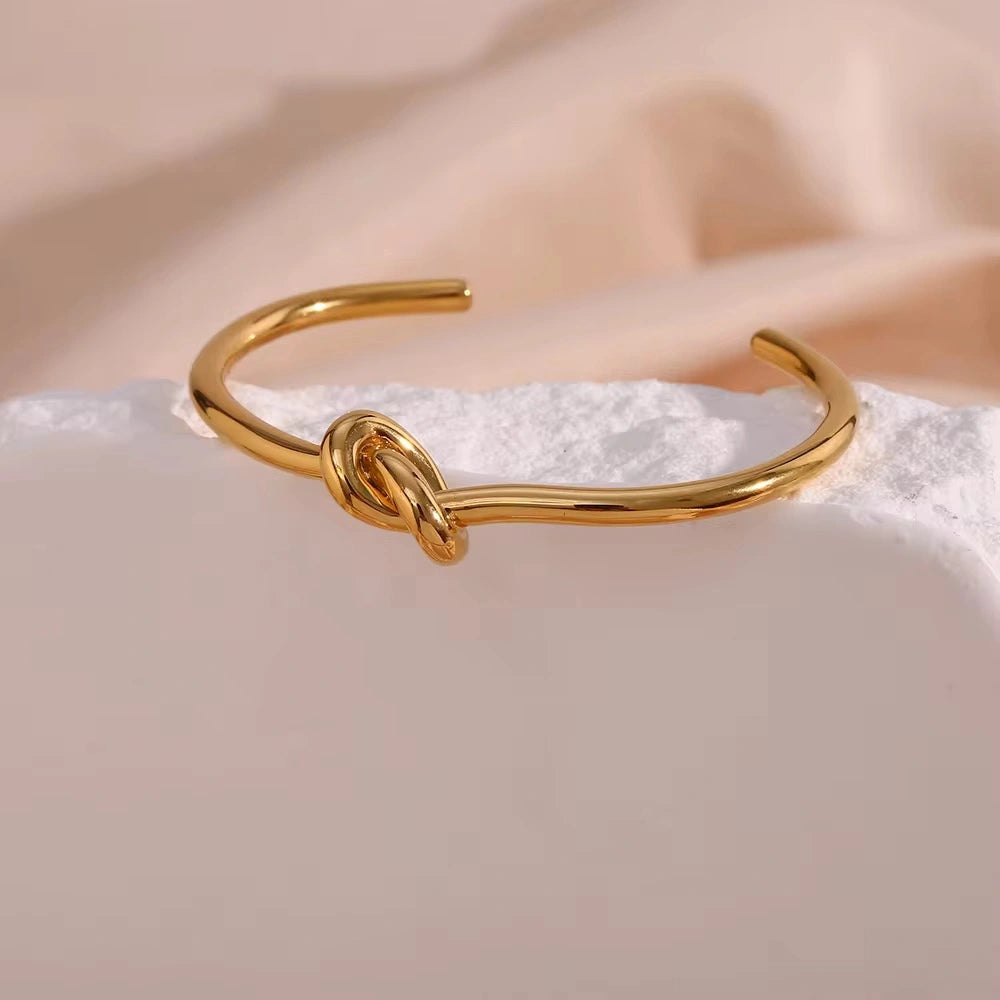 Gold bracelet with a knot design on a soft, light background