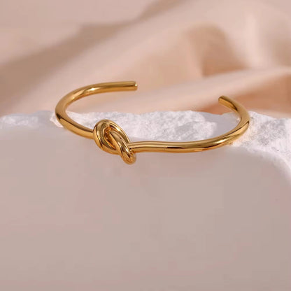 Gold bracelet with a knot design on a soft, light background