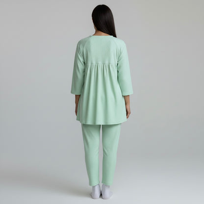 Person wearing a light green outfit on a plain background