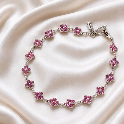 Pink clover bracelet with round pink stones and clear center gems in silver tone, worn on wrist close-up