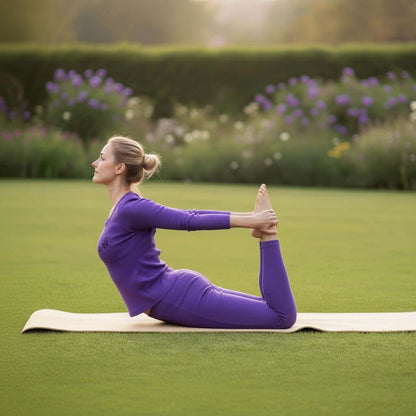 Woman in purple activewear doing yoga pose on mat outdoors in green park