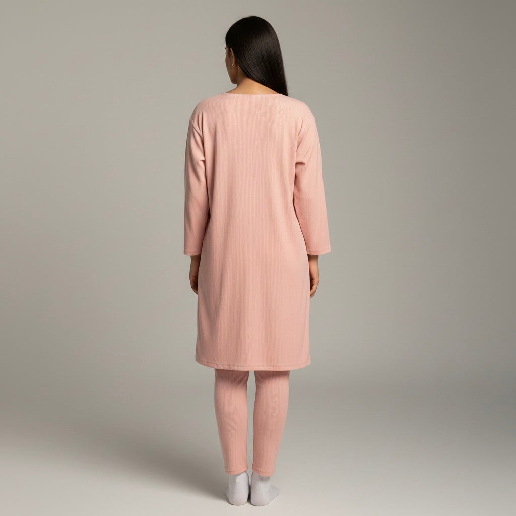 Woman wearing a pink dress and pants set on a plain background