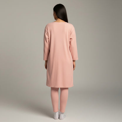 Woman wearing a pink dress and pants set on a plain background