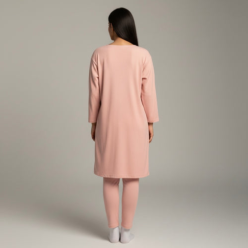 Woman wearing a pink dress and pants set on a plain background