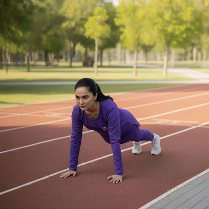 Woman in purple shirt and white pants on a running track with trees in the background