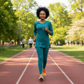 Woman jogging on outdoor running track in green athletic wear, park background, sunny day