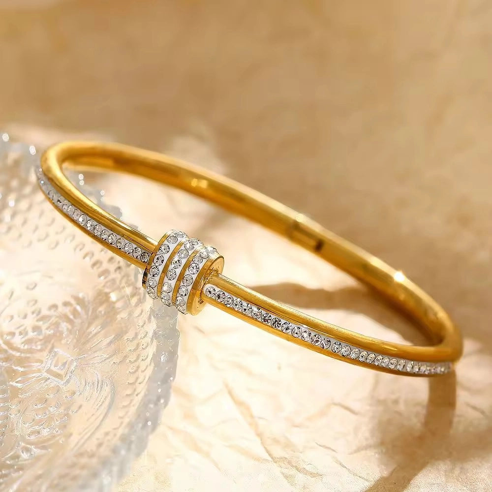 Gold bracelet with diamond accents on a beige background