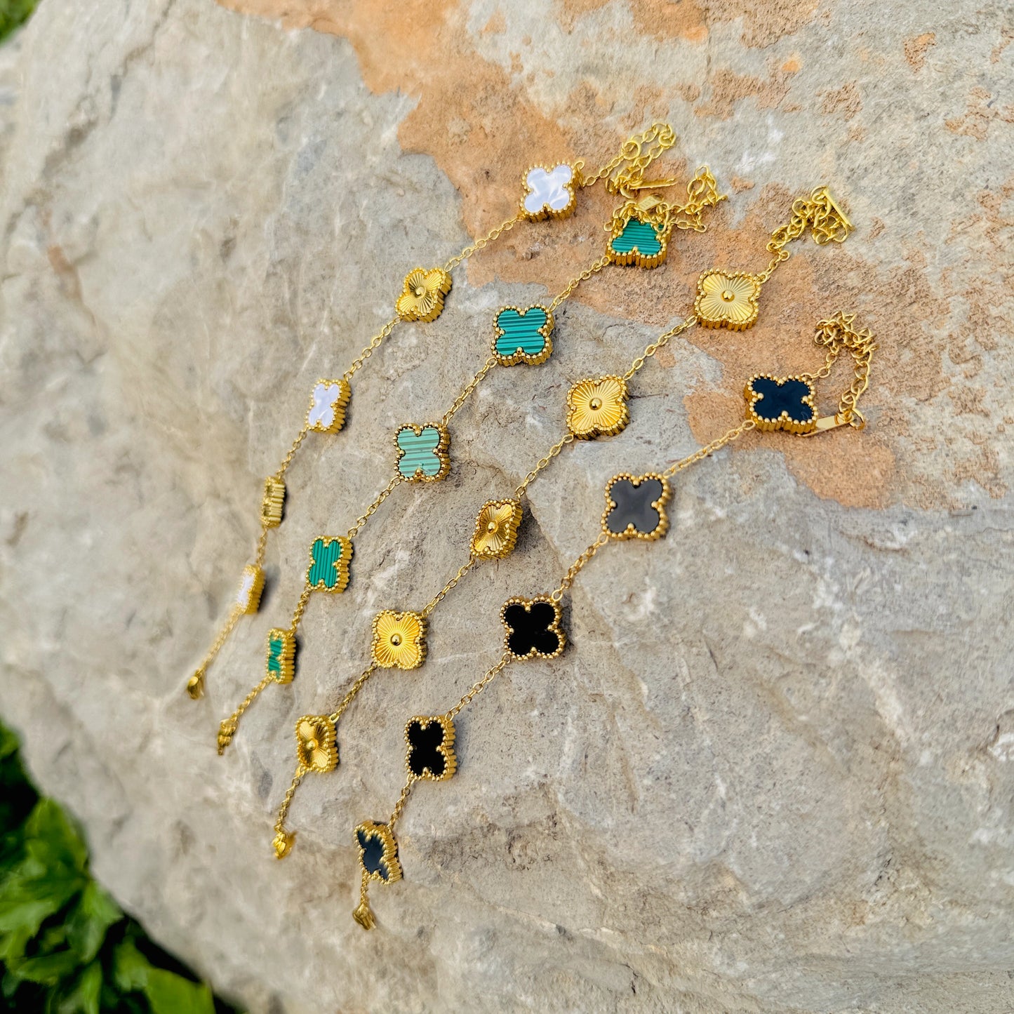 Gold necklace with colorful pendants on a stone surface