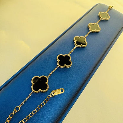 Gold necklace with black clover-shaped pendants on a blue box