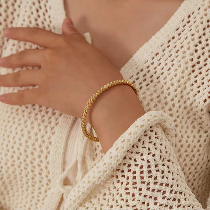 Gold bracelet on a wrist with a textured white garment