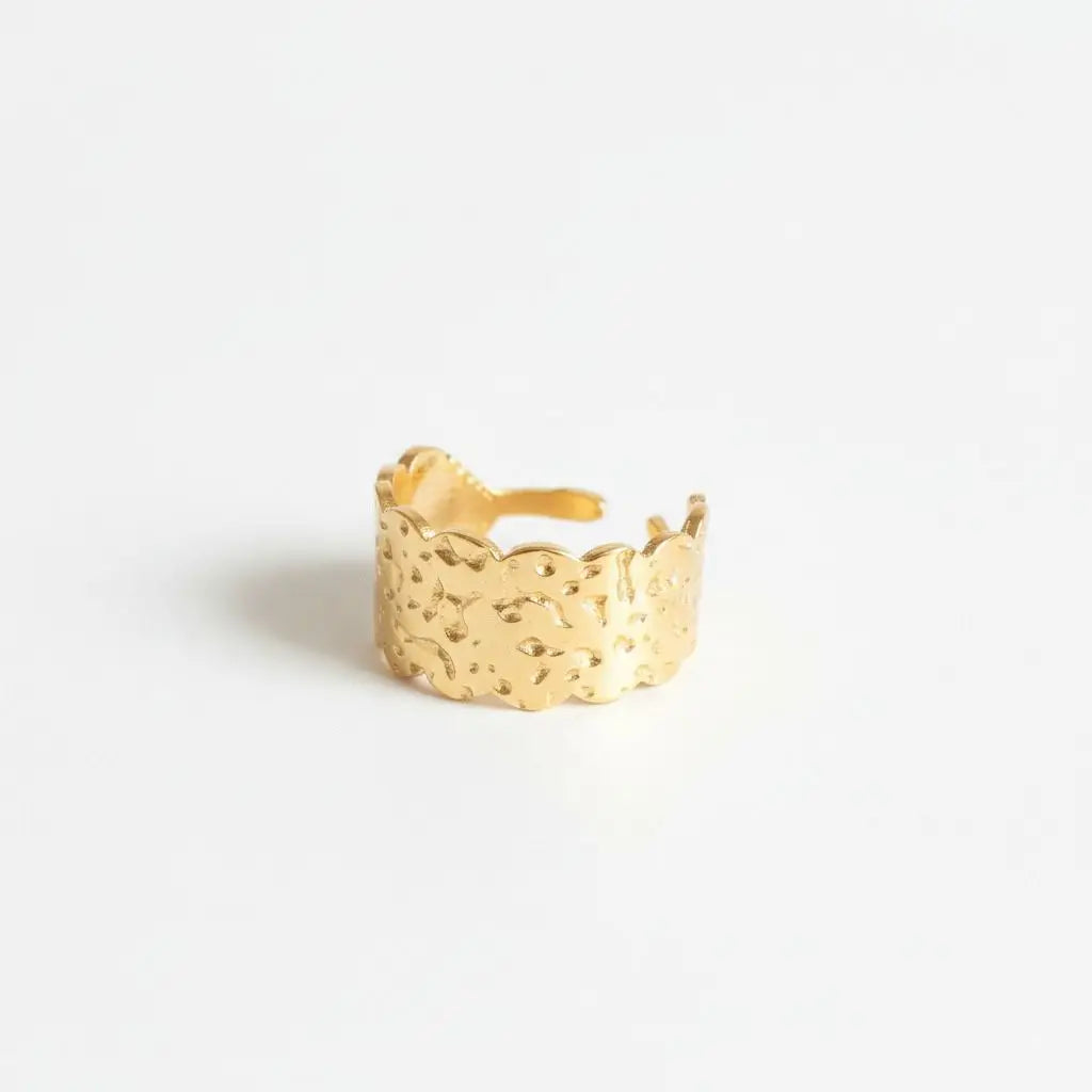 Gold ring with textured design on a light gray background