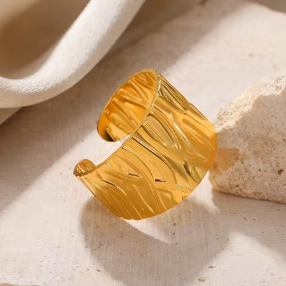 Gold cuff bracelet on a textured beige surface
