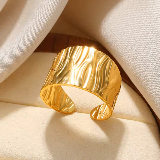 Gold cuff bracelet on a beige fabric background
