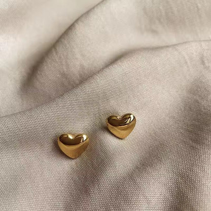 Gold heart-shaped earrings on a light fabric background