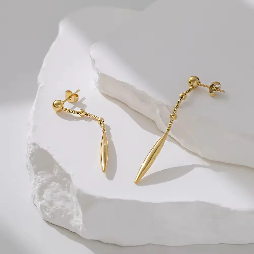 Gold earrings on a textured white surface