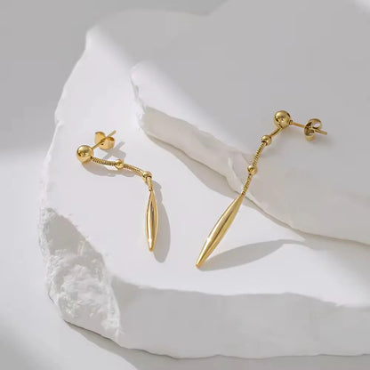 Gold earrings on a textured white surface