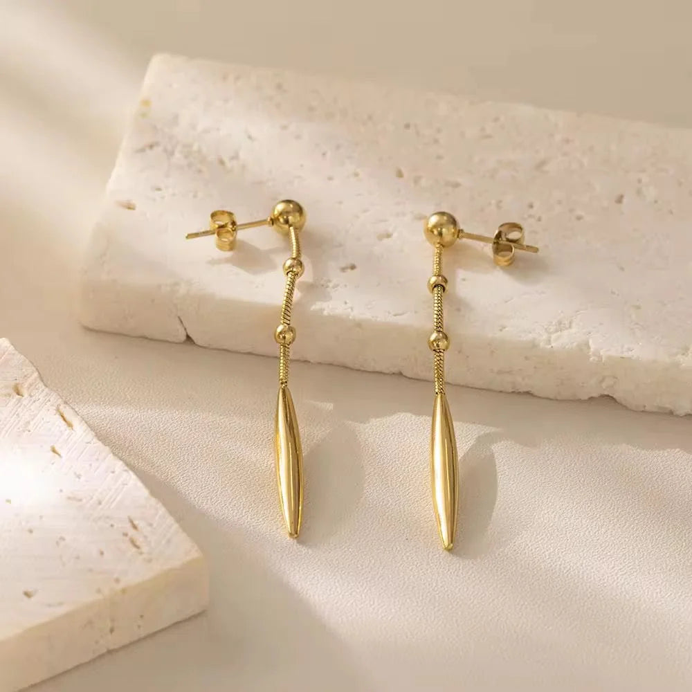 Gold earrings on a textured beige surface