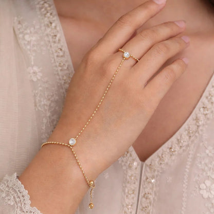 Close-up of a hand wearing a gold bracelet and ring with a delicate flower design.
