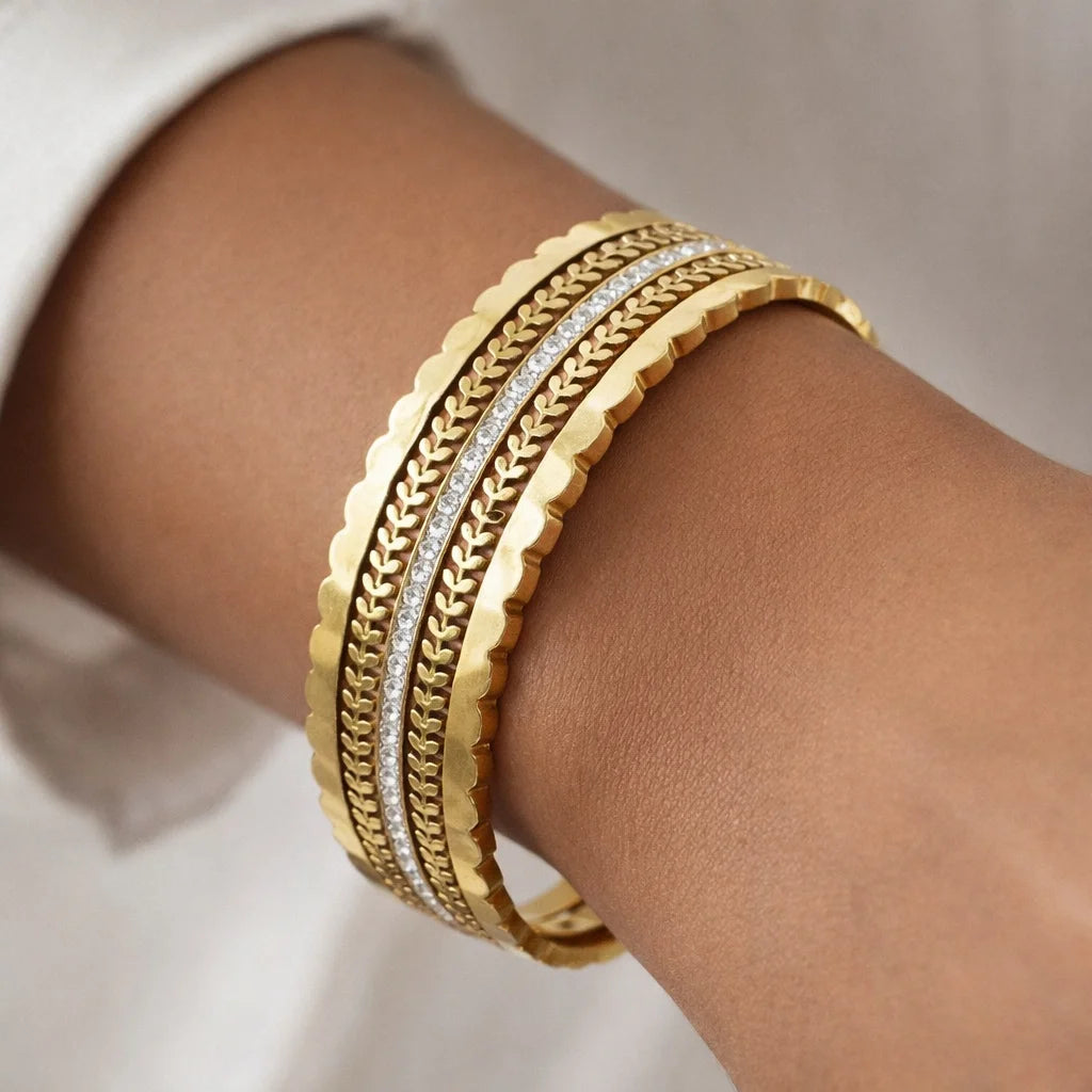 Gold bracelets on a wrist with a neutral background