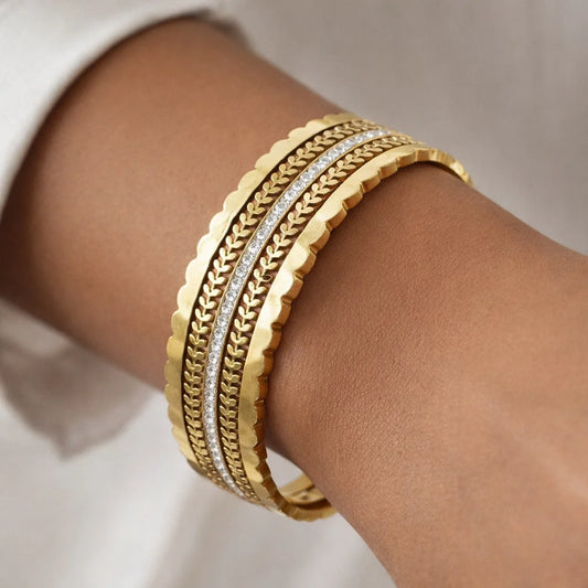 Gold bracelets on a wrist with a neutral background
