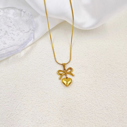 Gold necklace with a heart-shaped pendant on a white textured surface