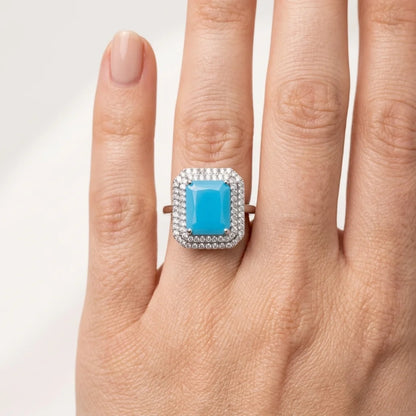 Ring with a blue gemstone on a hand against a light background