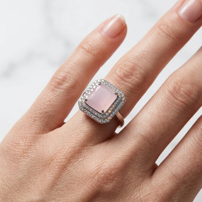 Ring with a pink gemstone on a finger against a white background