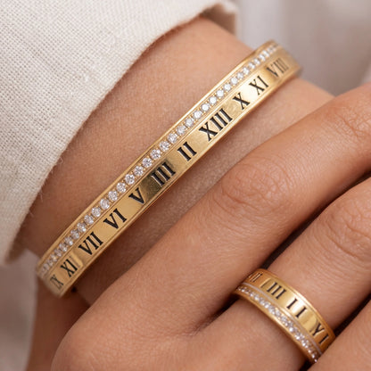 Gold bracelet with Roman numeral design on a wrist