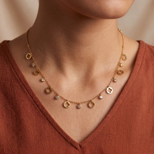 Gold necklace with circular pendants on a person wearing a rust-colored top.