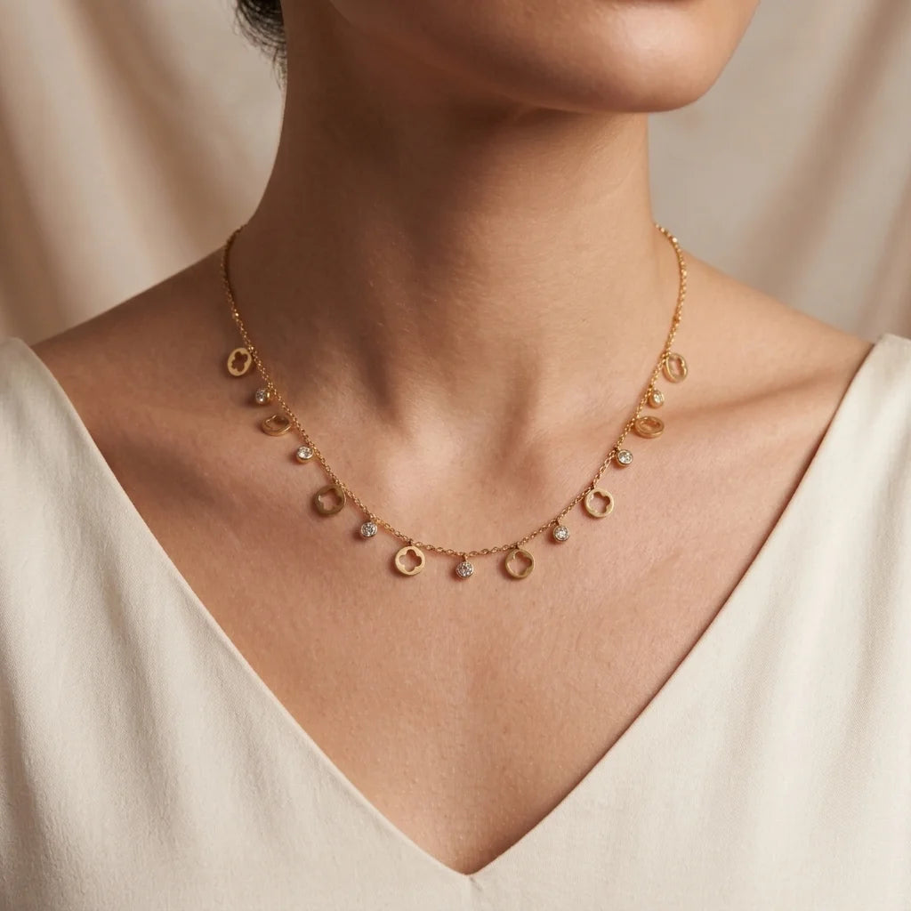 Gold necklace with small circular pendants on a neutral background