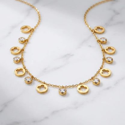 Gold necklace with heart-shaped pendants on a marble surface