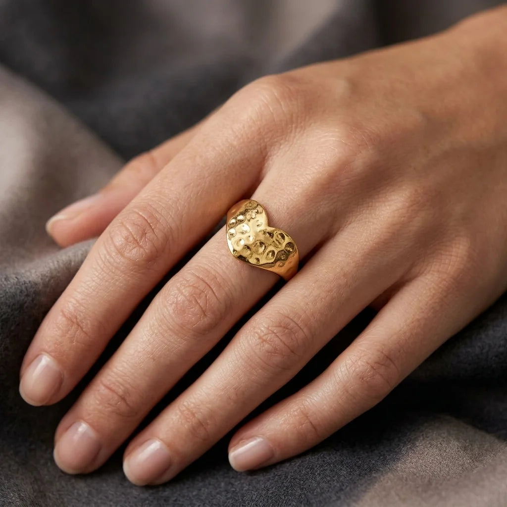Gold ring on a person's finger against a gray fabric background
