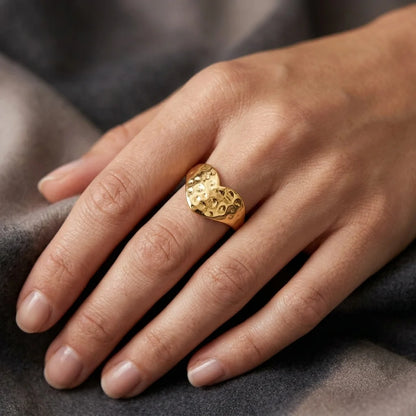Gold ring on a person's finger against a gray fabric background