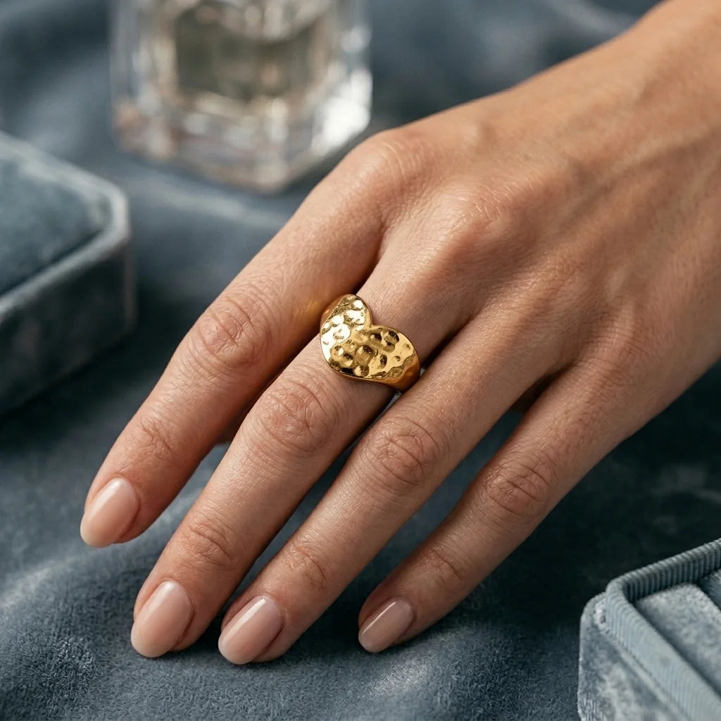 Gold ring on a person's finger against marble background
