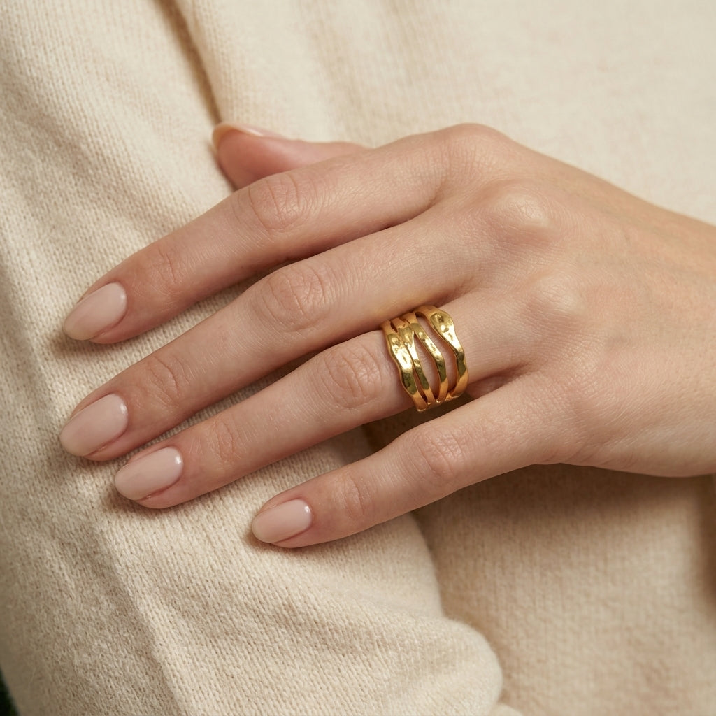 Hand wearing a gold ring on a beige background