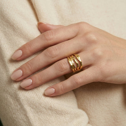Hand wearing a gold ring on a beige background