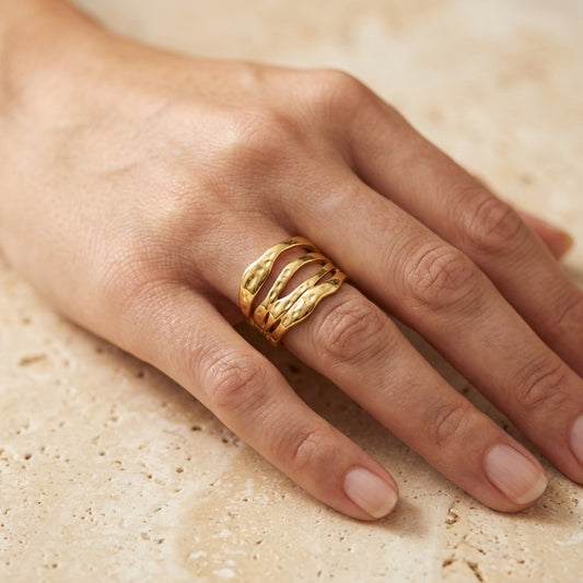 Gold ring on a finger against a beige background