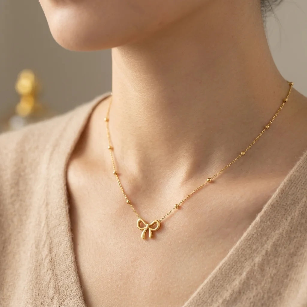 Gold necklace with a bow pendant worn by a person in a neutral setting