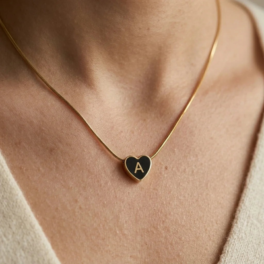Gold necklace with a heart-shaped pendant featuring the letter 'A' on a person's neck.