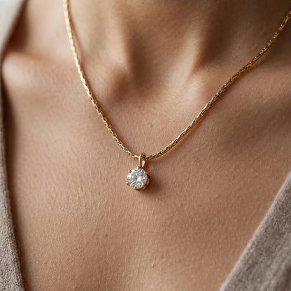 Gold necklace with a diamond pendant on a person's neck