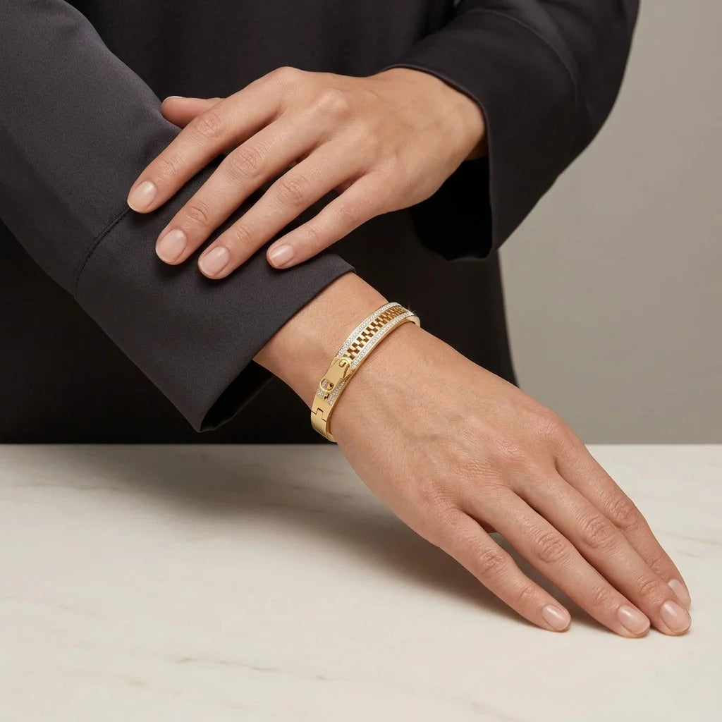 Hand wearing a gold bracelet on a neutral background